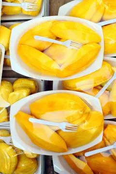 Pieces of mango in a plastic plate with a fork on the counter Foto stock