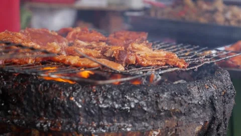 Pieces of meat cook on a grill over hot charcoal at a local market food stall. B Vídeo Stock 342140018
