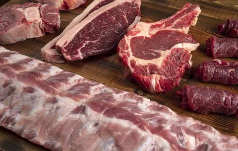 Pieces of meat of different types on the board. beef and pork. Stock Photos