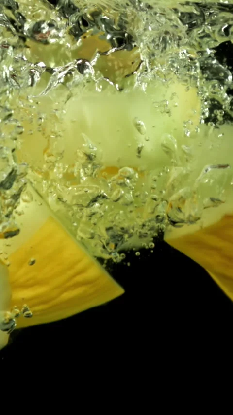 Pieces of melon falling under water on a black background. Filmed on a high Stock Footage 335372569