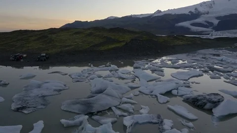 Pieces of melted glacier and two cars camping on the shore Stock Footage 74907120