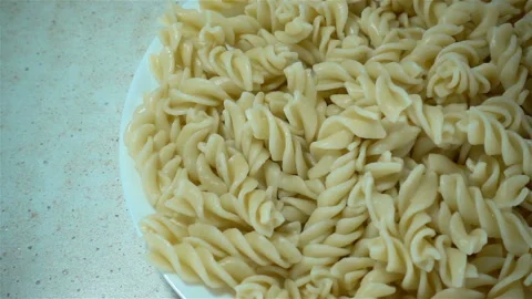 Pieces of paste fall in slow motion into a plate full of pasta. Stock Footage 126896843