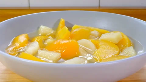 Pieces of peach, pear, pineapple and apricot in a bowl with juice. Stock Footage 192394975