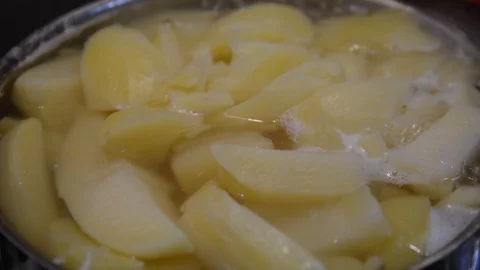 Pieces of potatoes are boiled in a pan on a gas stove. Stock Footage 120947862