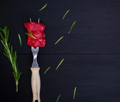 Pieces of raw beef on kitchen fork with plastic handle Photos