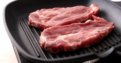 Pieces of raw meat are placed on a grill pan. Stock Footage 250277301