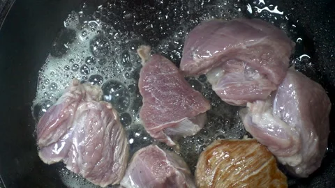 Pieces of raw meat fall in slow motion into the pan. Video stock 134732553