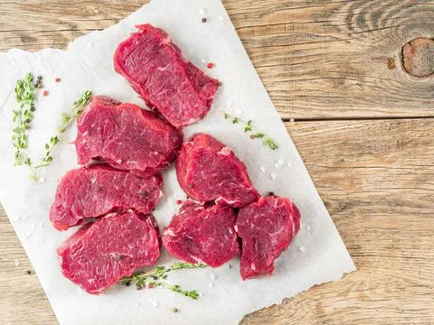 Pieces of raw meat. Raw beef with spices and thyme on white parchment paper on Foto stock