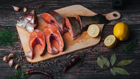 Pieces of red fish on the Board on the table in the kitchen for cooking. Sliced Stock Photos