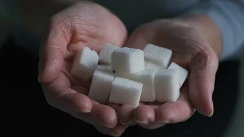 Pieces of refined sugar in the hands of an elderly woman, close-up Stock Footage 258775760