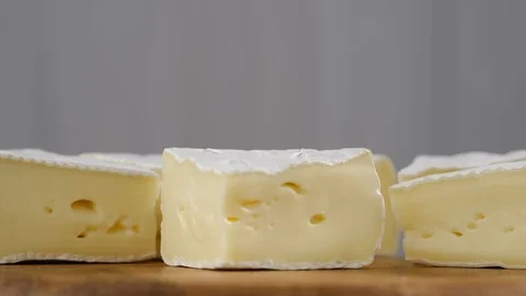 Pieces of soft cheese Camembert on light grey background, rotation. Stock Footage 129216686