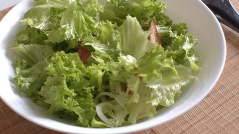 Pieces of sweet pepper fall on a vegetarian salad in a white bowl Stock Footage 79392089