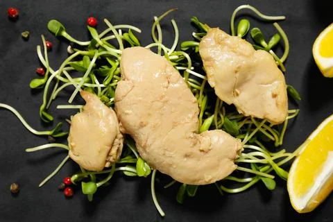 Pieces of tasty cod liver and herbs on black plate as background, closeup Stock Photos