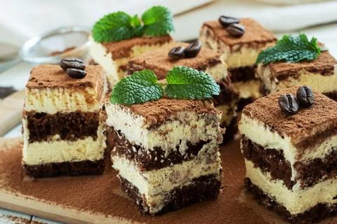 Pieces of tiramisu cake with delicate cream, coffee beans and mint leaves. 写真素材