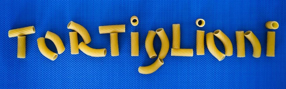 Pieces of tortoglioni pasta on a blue background forming the word "TORTIGLION Stock Photos