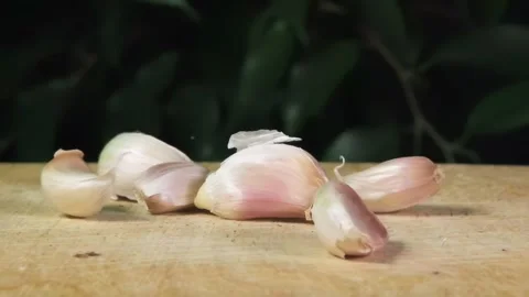 Pieces of unpeeled garlic fall on the table, slow motion, proper nutrition Stock Footage 264877536