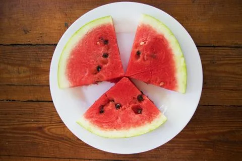 Pieces of watermelon in bowl and slice on white plate. Top view Stock Photos