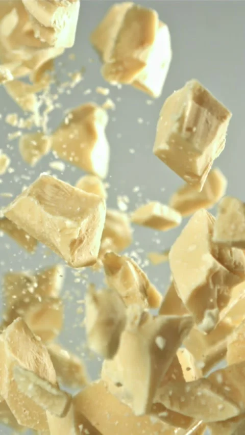 Pieces of white chocolate fly up and fall down. Filmed on a high-speed camera at Stock Footage 335359586