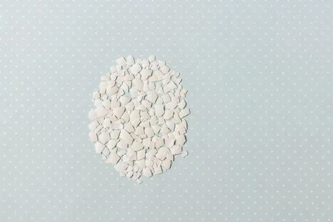 Pieces of white shell chicken egg, folded in the shape of an egg on a blue ba Stock Photos