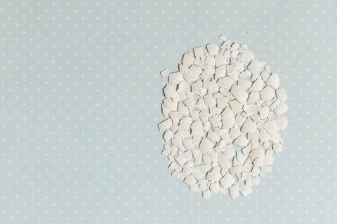 Pieces of white shell chicken egg, folded in the shape of an egg on a blue ba Stock Photos