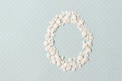 Pieces of white shell chicken egg, folded in the shape of an egg on a blue ba Stock Photos