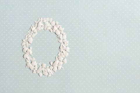 Pieces of white shell chicken egg, folded in the shape of an egg on a blue ba Stock Photos