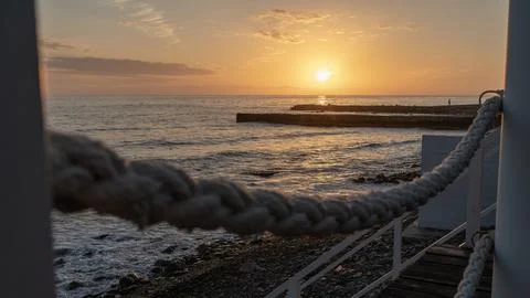 Pier and breakwaters in the rays of the setting sun at sunset. Autumn seascap Stock Photos