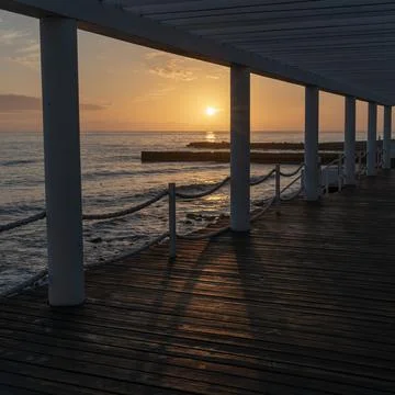 Pier and breakwaters in the rays of the setting sun at sunset. Autumn seascap Stock Photos