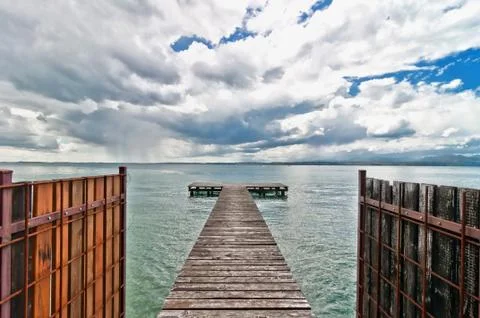Pier and cloudy dramatic sky over Garda lake - Italy Stock Photos
