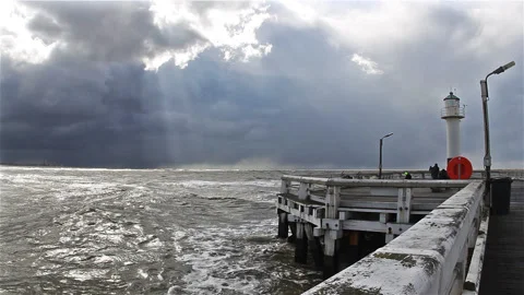 Pier and lighthouse under changing sky with dark clouds Stock Footage 89656773