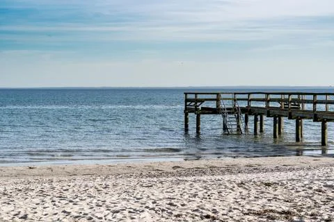 A pier is on the beach next to the ocean Stock Photos