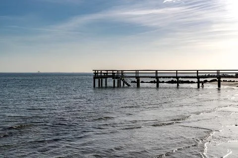 A pier is on the beach next to the ocean Foto stock