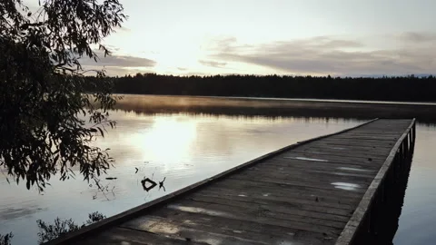 The pier in the depths of the lake under the rays of the setting sun in autumn Stock Footage 220565994