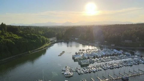 Pier with gold sunset, distant mountains, blue sky, lush green trees, sailboats Stock Footage 155725603