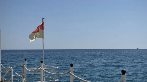 Pier with a lifeguard flag fluttering in a light breeze of Mediterranean sea Stockbeeldmateriaal 69000254