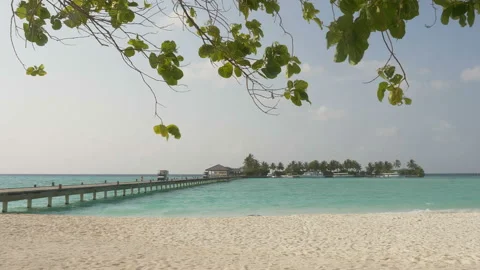 Pier over the blue ocean leading to a beautiful island with a white beach and Stock-Footage 90685630