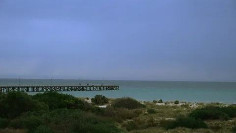 Pier over emerald ocean and sand dune beach with pier Stock Footage 99286253