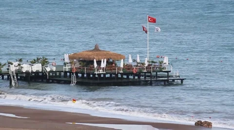 Pier with the restaurant on the ocean. Waves suffering crash on a beach and sand 動画素材 7746463