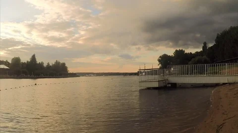 Pier on the sandy shore of a pond at sunset 스톡 동영상 82371068