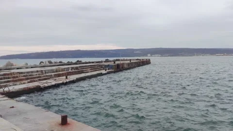 Pier in the sea and waves moving in a cloudy day Stock Footage 233463205
