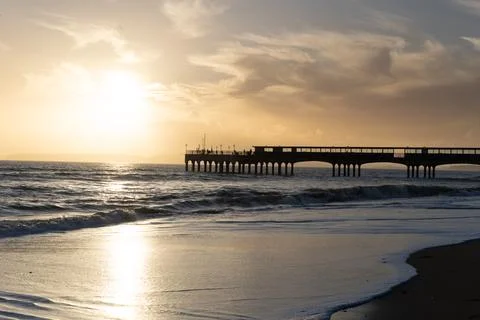 Pier At Sunset With Waves Breaking Stock Photos