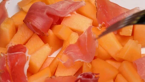Piercing melon and ham with a fork. orange melon with hamon. Stock Footage 283727124