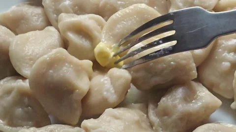 Piercing a Piece of Butter with a Fork on Hot Dumplings in a Plate Stock Footage 345454118
