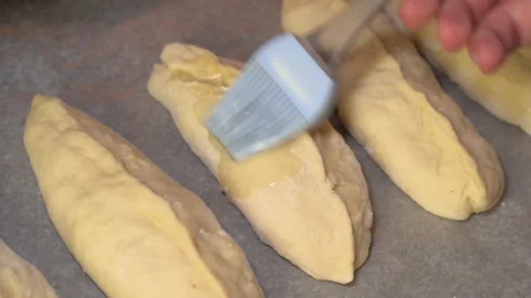 Pies on a baking sheet are coated with sunflower oil before baking Stock Footage 254167927