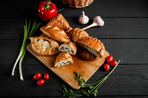 Pies on a cutting board. Composition on a black background with ingredients.. Stock Photos