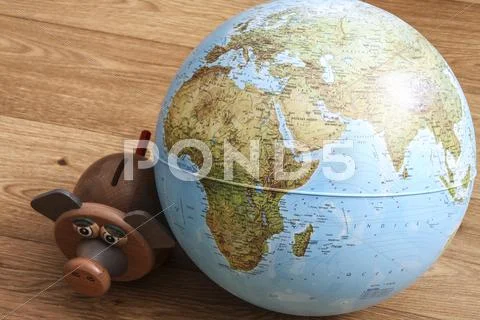 Pig money box with hand with coin and globe. pig is staring at globe. Stock Photos