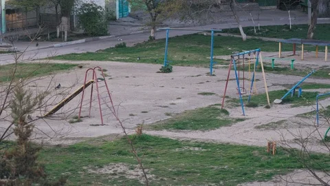 Pigeons walk around the yard with an empty big playground in covid 19 Stock Footage 128015792