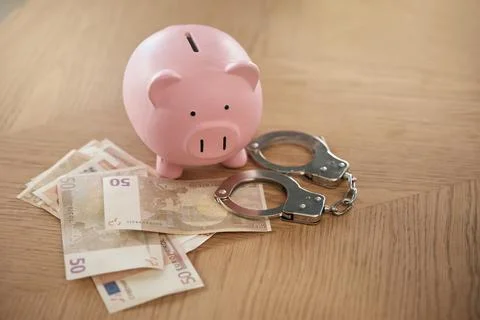 Piggy bank, handcuffs and finance money laundering of economy paper currency Stock Photos