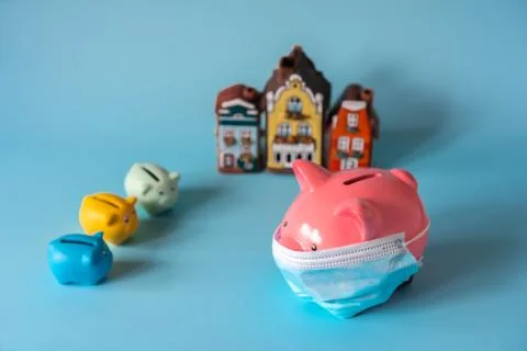Piggy bank with medical mask, small piggy banks and house models Stock Photos