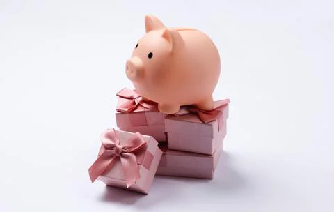 Piggy bank on stack of gift boxes. White background Foto stock